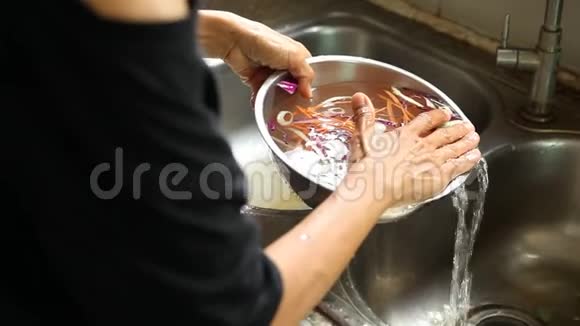 女人在厨房水槽里洗绿色沙拉叶子视频的预览图