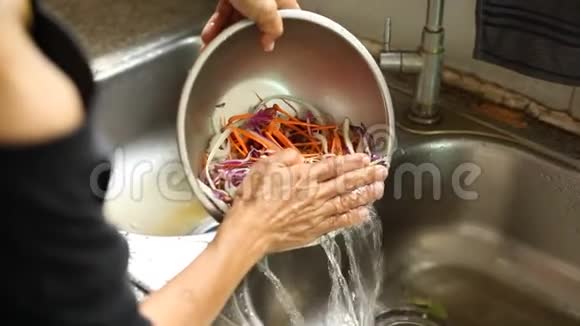 女人在厨房水槽里洗绿色沙拉叶子视频的预览图
