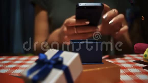 特写女性在智能手机上拍摄一个蓝色小秘密礼物盒的照片视频的预览图