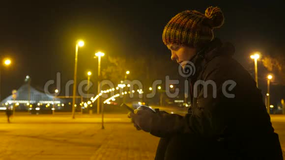 女孩手里拿着一部电话在夜城背景下聊天4K视频视频的预览图