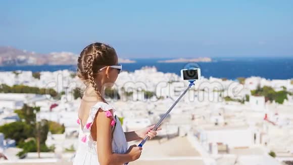 可爱的小女孩自拍照片背景Mykonos镇希腊视频的预览图