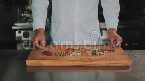 男性厨师长白色长袍把香料从木切割板上扔下来视频的预览图