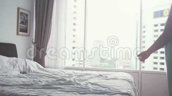年轻漂亮的女人用电话而躺在公寓的床上全景窗慢动作3840x2160视频的预览图