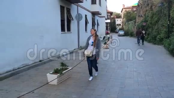 黄昏时分一个背着包的年轻女子沿着欧洲老街散步视频的预览图