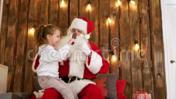 小女孩坐在老圣诞老人的腿上刷胡子视频的预览图
