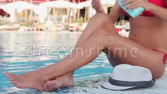 有着大腿的女孩用奶油在游泳池边晒黑视频的预览图