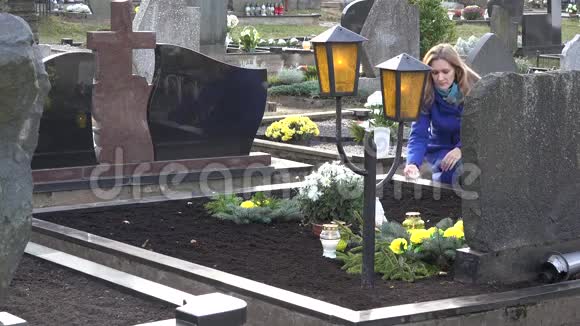 伤心的女人在墓地里把蜡烛放在爱父兄弟的坟墓上4K视频的预览图
