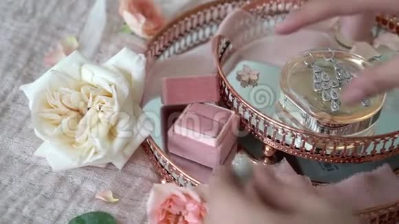 女人把珠宝戒指放在粉红色托盘的盒子里上面有新娘耳环求婚戒指和香水视频的预览图