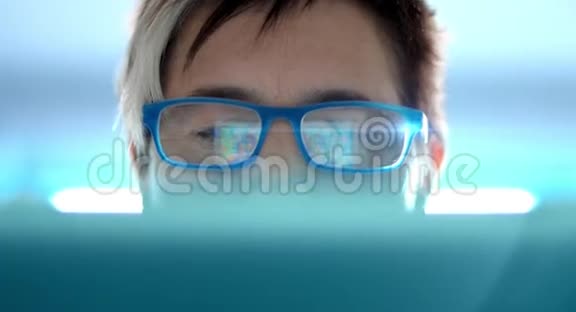 4K一个女人正在用平板电脑玩一个在线游戏这在她的眼镜里有反映她的脸上有一个笔记本视频的预览图