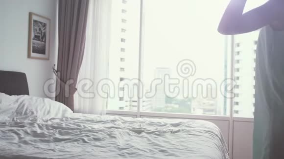 年轻漂亮的女人用电话而躺在公寓的床上全景窗慢动作3840x2160视频的预览图
