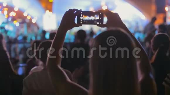 年轻女子在智能手机上录制音乐音乐会视频视频的预览图