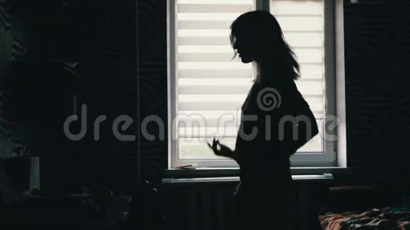 一个女孩在家窗前跳舞的剪影视频的预览图