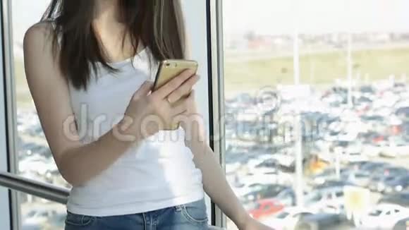窗户附近的漂亮女孩带着智能手机视频的预览图
