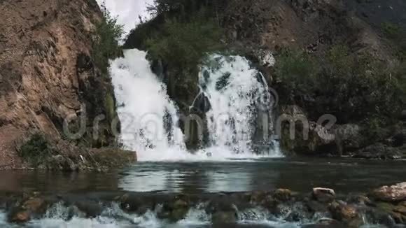 在一片深林中一个小瀑布的近处美丽的小旅游瀑布一个小湖掉进了视频的预览图