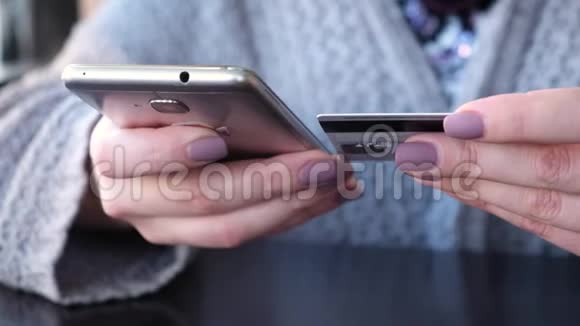 年轻的高加索女性用信用卡在智能手机上从互联网上购买商品视频的预览图