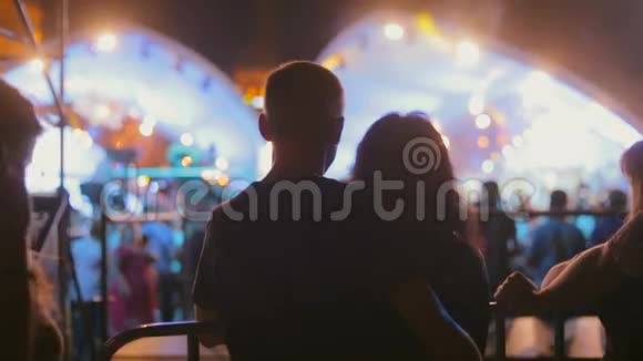 一对相爱的情侣在晚上的音乐会上拥抱的剪影视频的预览图