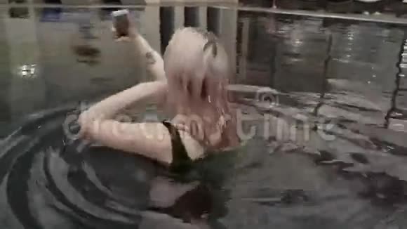 美丽的年轻女孩在iPhone上自拍池中股票视频视频的预览图
