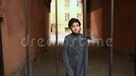 一个无家可归的少年透过铁栅栏看着摄像机视频的预览图
