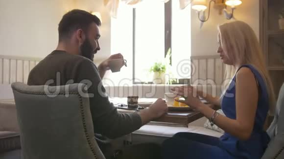 快乐的一对夫妇在咖啡馆里享受甜点和牵手视频的预览图