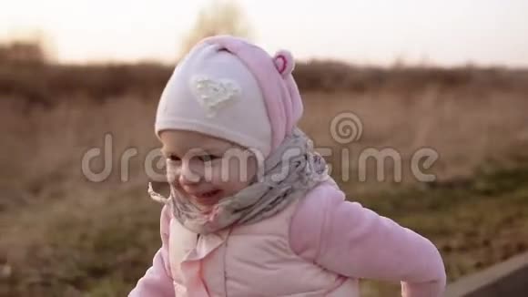小女孩穿着粉红色的衣服慢动作地奔跑着笑着看日落视频的预览图