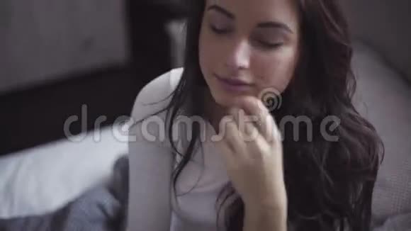 害羞英俊的年轻女人坐在床上做姿势视频的预览图