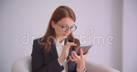 用平板电脑拍摄白种人年轻女商人戴眼镜的特写肖像并用绿色的彩色屏幕拍摄视频的预览图