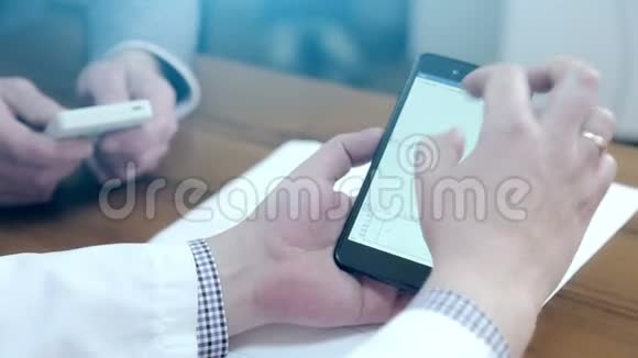 医生用手机和平板电脑使用电子设备的男性医生视频的预览图