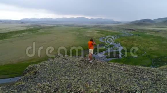 专业的自然摄影师带着相机在山顶上环顾四周拍摄空中慢镜头视频的预览图