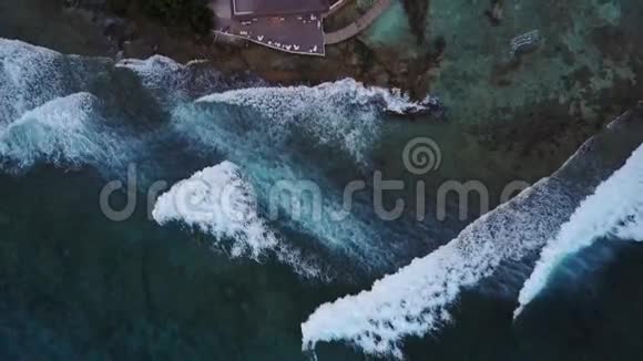空中无人机摄像机正在降落到热带岛屿白色沙滩和度假胜地棕榈树影平房视频的预览图
