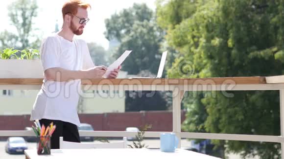 年轻设计师阅读文件站在阳台室外视频的预览图