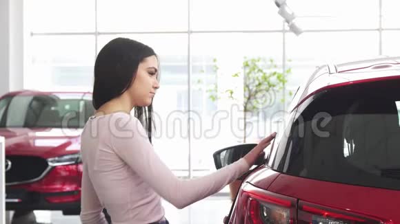 快乐的女人在汽车经销商使用智能手机视频的预览图