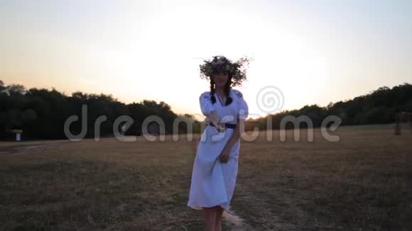 在草地上散步的女孩穿着花圈在大自然的夕阳下穿着民族服装视频的预览图