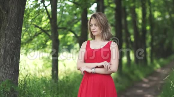 绿色bokeh背景上穿红色裙子的年轻女人的肖像慢动作视频的预览图