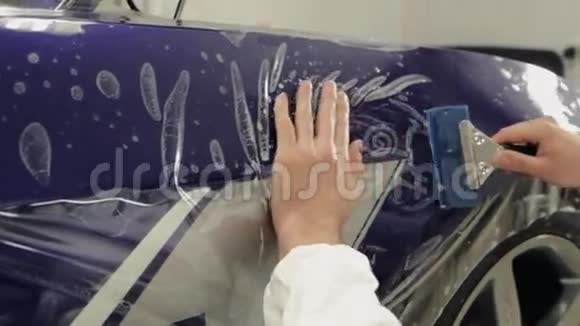 服务站的工人在一辆昂贵的汽车上粘贴乙烯基视频的预览图
