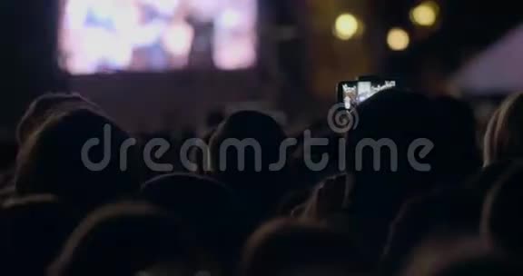 在狂欢派对中人们用手拿着数码显示的相机观看灯光视频的预览图