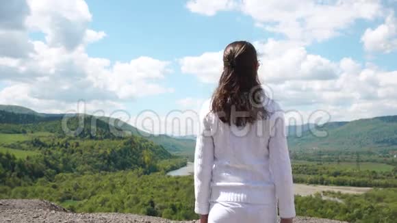 年轻女子走到山的边缘张开双手感到自由视频的预览图