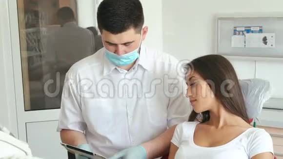 牙科医生向牙医室的女性病人解释手术视频的预览图