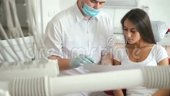 牙科医生向牙医室的女性病人解释手术视频的预览图
