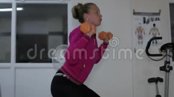 年轻漂亮的女孩在健身房里用哑铃做运动视频的预览图