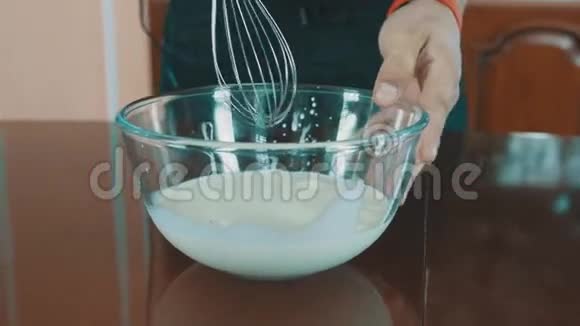 糕点厨师开始用搅拌器将牛奶混合到玻璃碗里视频的预览图