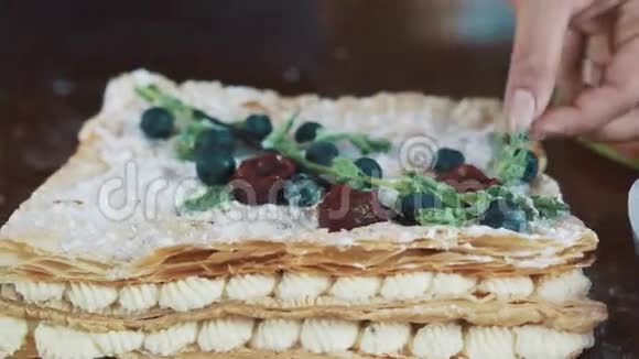 女性的手用薄荷叶装饰糖粉覆盖的分层蛋糕视频的预览图