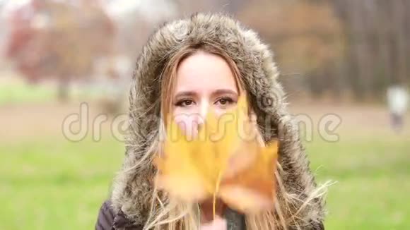 年轻女子拿着叶子在脸前移动它做有趣的脸视频的预览图