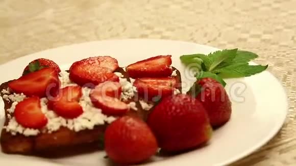 在一张白色盘子里的桌子上放着一小罐干酪和草莓的烤面包视频的预览图