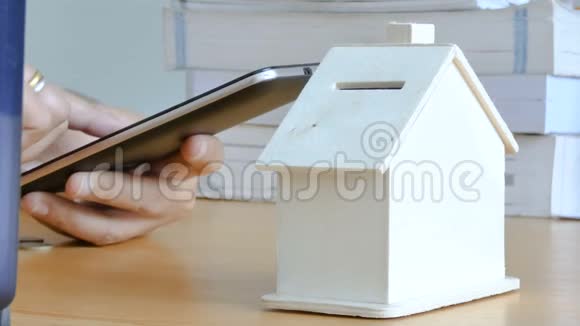 女人的手用智能手机电脑把钱币放进储蓄罐里隐喻手机应用计算视频的预览图