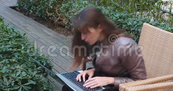 带笔记本电脑的年轻商务女性在露台咖啡厅视频的预览图