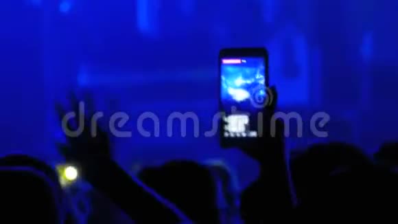 摇滚音乐会上的人们正在使用智能手机在社交网络上直播视频的预览图