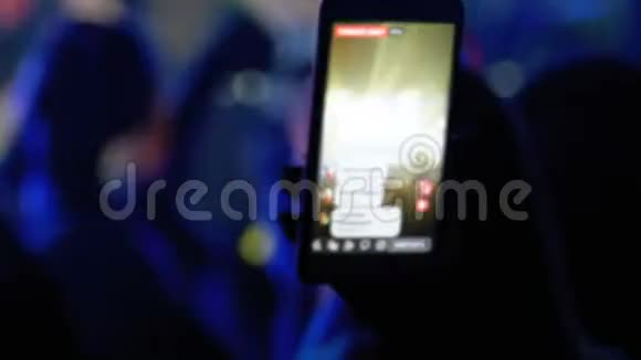 摇滚音乐会上的人们正在使用智能手机在社交网络上直播视频的预览图