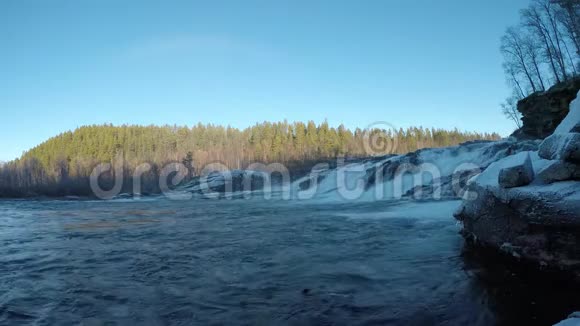 深秋早晨在阳光下巨大的冷瀑布色彩斑斓的森林背景和巨石上的冰霜视频的预览图