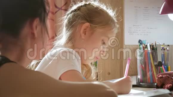 年轻的母亲在台灯下帮女儿做作业视频的预览图