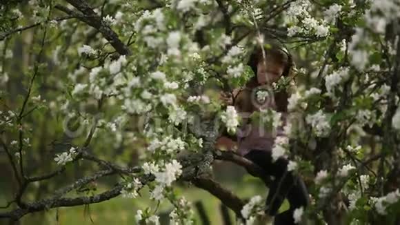 小女孩坐在树枝上戴着耳机听音乐视频的预览图